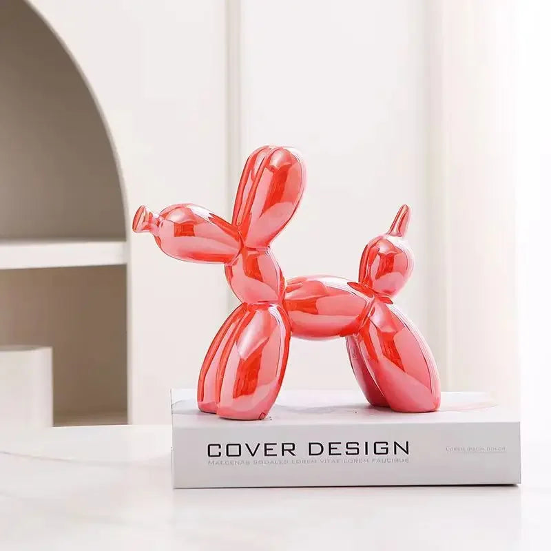 Sculpture chien ballon rouge effet miroir, objet décoratif pop art sur un livre de design, dans une ambiance moderne et lumineuse