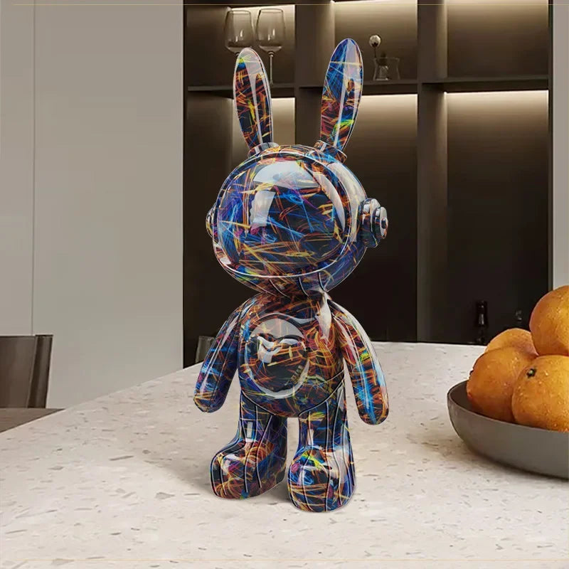Statue de lapin astronaute design au motif graffiti abstrait bleu et multicolore, exposée sur une table moderne dans un intérieur chic
