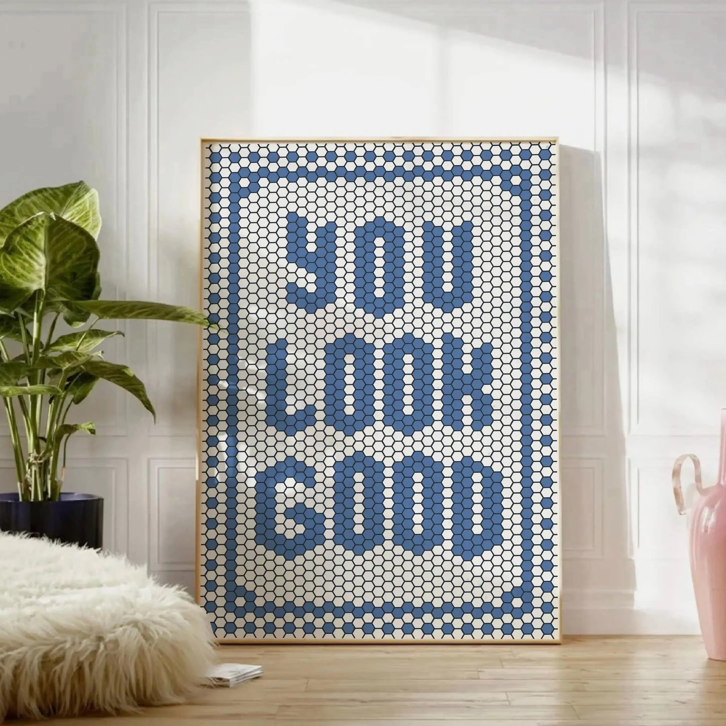 Affiche typographique design bleu avec message “You Look Good” en mosaïque de style pixel, encadrée et posée au sol dans un intérieur moderne.