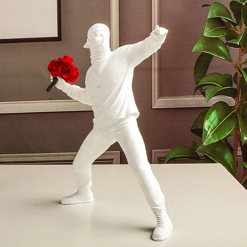Statue blanche inspirée de Banksy représentant un manifestant lançant un bouquet de roses rouges, décor murale pop art au style contemporain et engagé