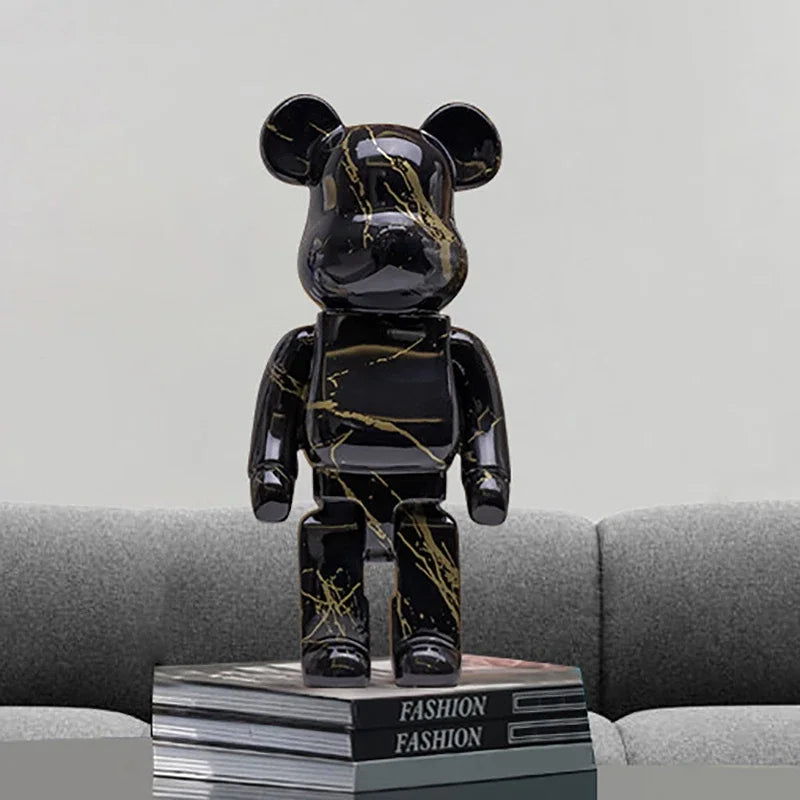 Figurine déco ours noir style Bearbrick avec motifs graffiti pop art sur canapé gris