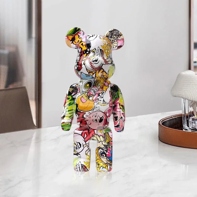 Figurine bearbrick pop art multicolore avec motifs cartoons, décoration originale posée sur une table en marbre dans un intérieur moderne