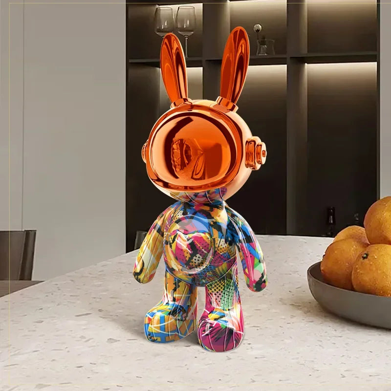 Sculpture lapin astronaute au casque orange métallisé, corps multicolore façon graffiti, posée sur une table design dans un intérieur modern