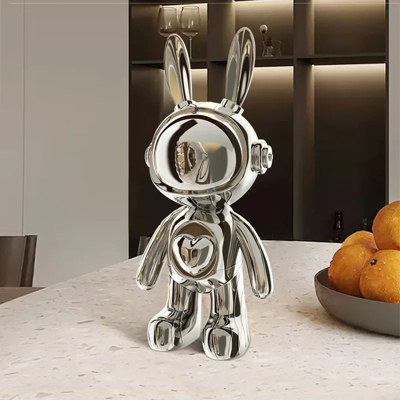 Sculpture lapin chromé en finition argent miroir, casque spatial et cœur sculpté sur le ventre, décoration pop art futuriste posée sur une table design
