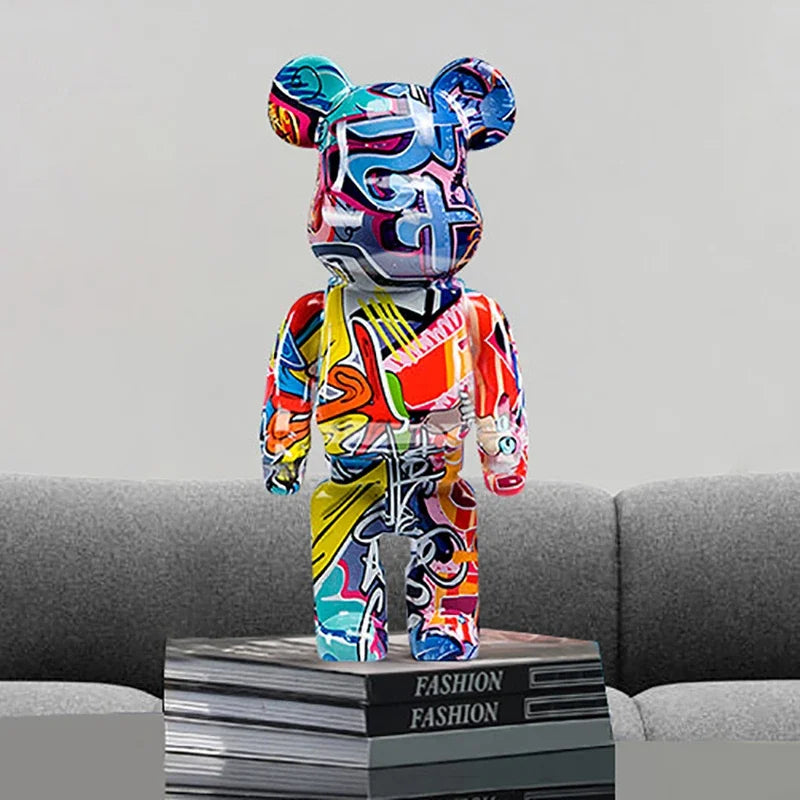 Figurine déco ours coloré style Bearbrick avec motifs graffiti pop art sur canapé gris