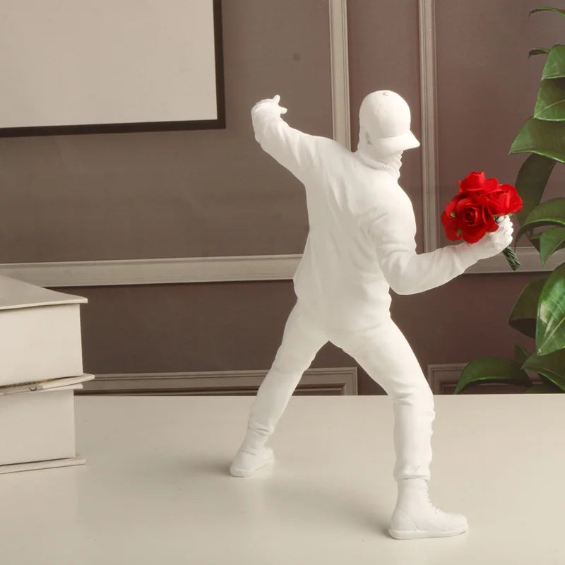 Statue blanche de dos inspirée de Banksy représentant un manifestant lançant un bouquet de roses rouges, décor murale pop art au style contemporain et engagé