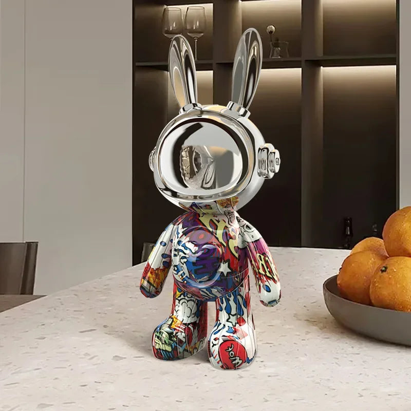 Statue design de lapin astronaute en chrome argenté avec combinaison graffiti multicolore, posée sur une table de cuisine moderne, ambiance urbaine et arty