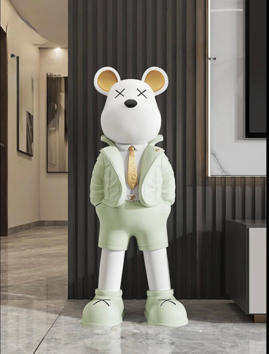 Sculpture décorative en forme d’ours blanc stylisé, vêtue d’une tenue verte pastel avec veste et cravate dorée, dans un intérieur moderne au style pop art