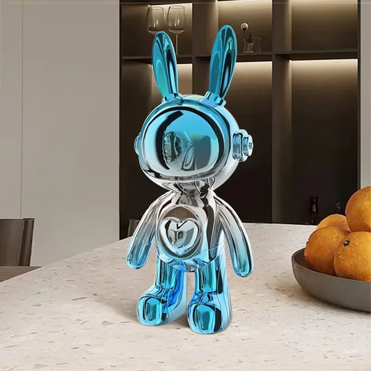 Figurine lapin design en résine chromée bleu ciel et argenté, style futuriste et pop art, posée sur une table en marbre dans un intérieur moderne