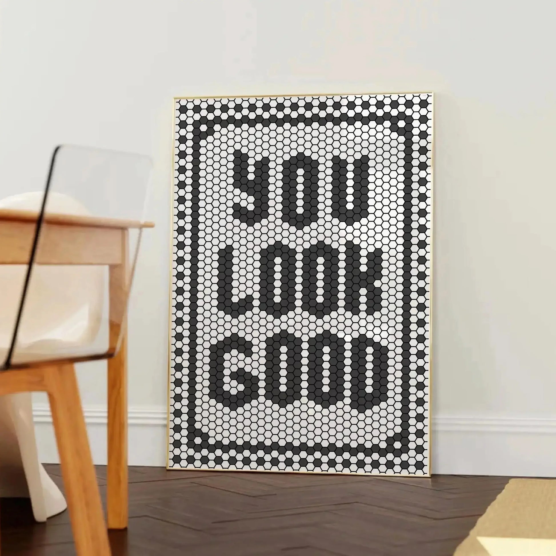 Affiche décorative typographique avec le message “YOU LOOK GOOD” formé par un motif de tuiles hexagonales noires et blanches, encadrée dans un cadre en bois clair, posée contre un mur blanc près d’une chaise design en bois et plexiglas.