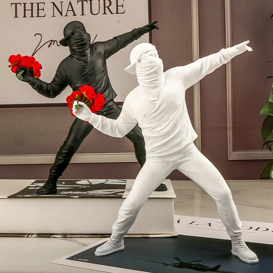 Duo dr Statue blanche et noir inspirée de Banksy représentant un manifestant lançant un bouquet de roses rouges, décor murale pop art au style contemporain et engagé