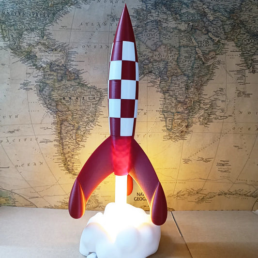 Objet déco fusée rouge à damiers blancs inspirée de Tintin, posée sur un socle nuage devant une carte du monde vintage, style rétro pop art