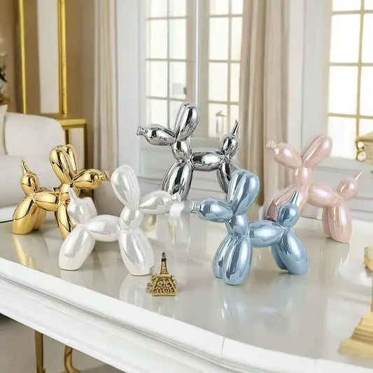 Collection de sculptures chien ballon effet miroir multicolores (doré, argenté, bleu, rose, blanc) posées sur une table blanche dans un salon lumineux au style classique chic