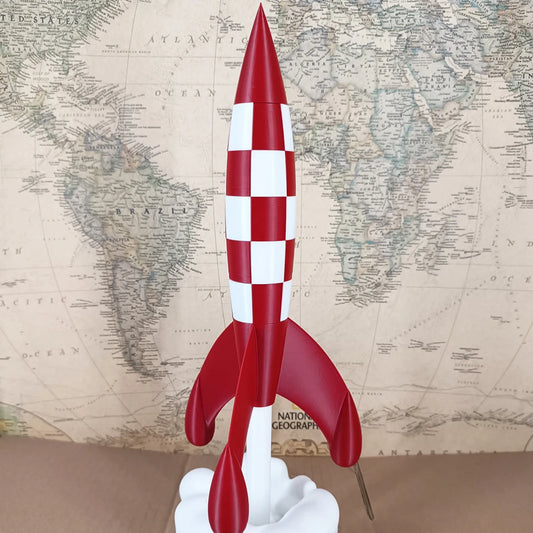 Objet déco fusée rouge à damiers blancs inspirée de Tintin, posée sur un socle nuage devant une carte du monde vintage, style rétro pop art